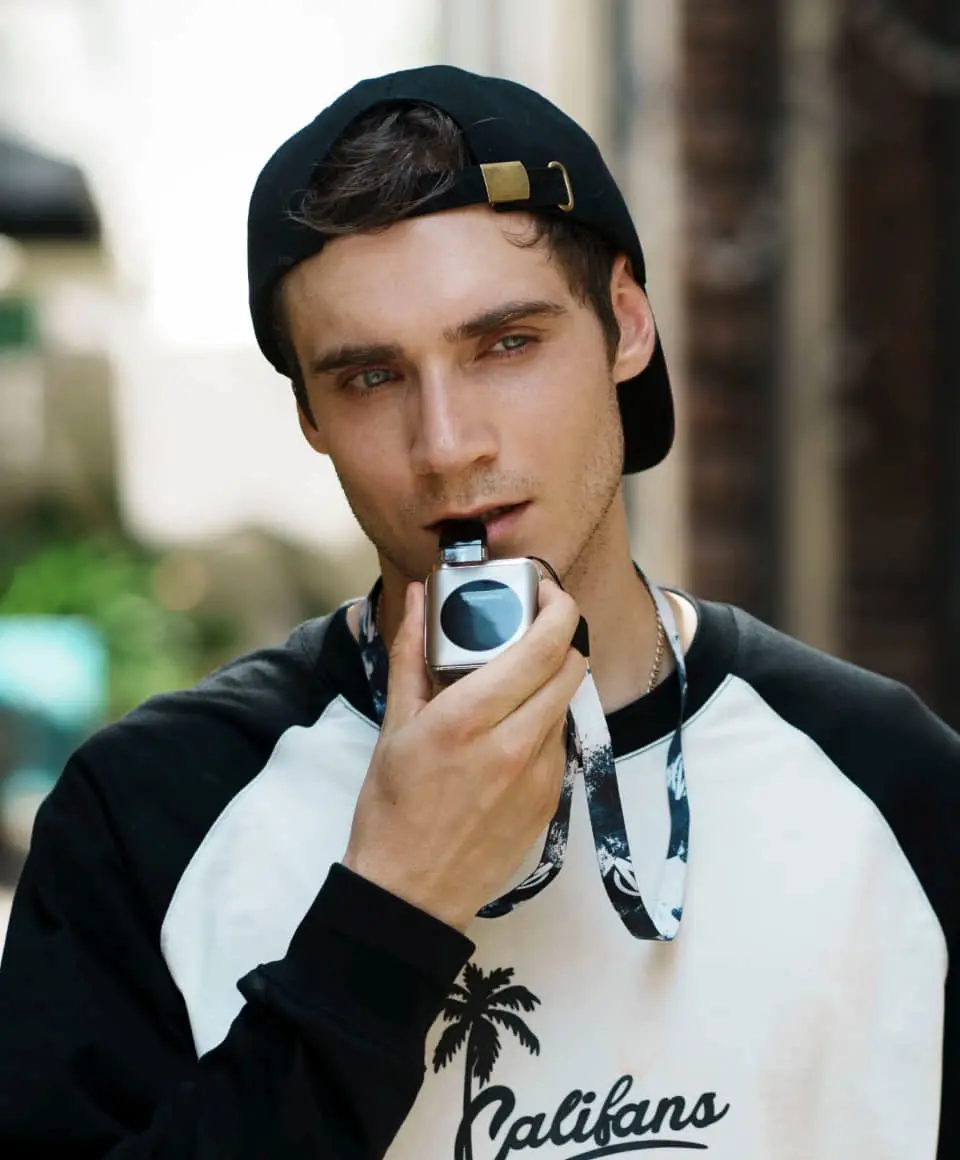 A user activating the Vaporesso XROS 4 NANO with the fire button. This button activation offers precise control, a key feature of the best mtl vape kit 2025.